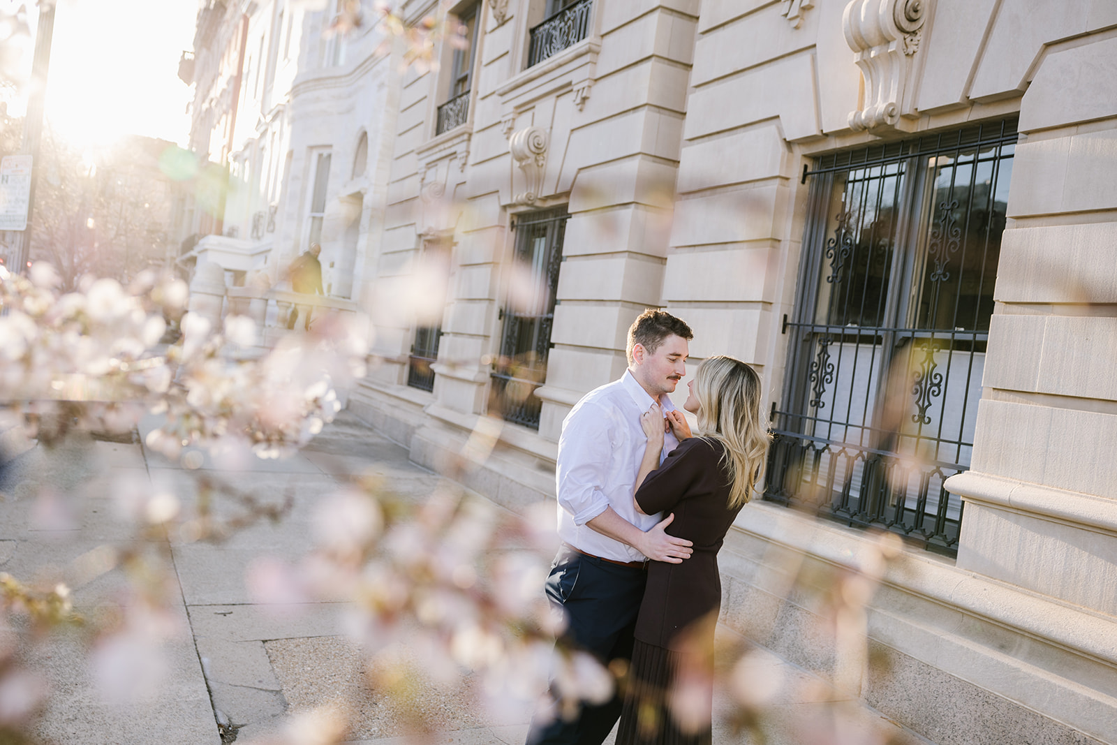 engaged couple shares a moment under the cherry blossoms in mt vernon baltimore