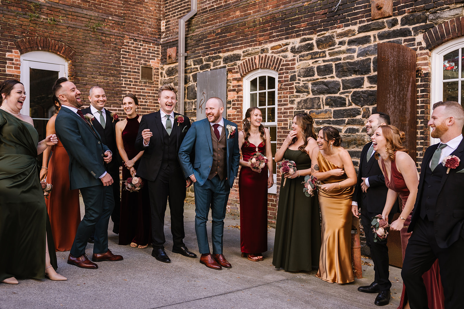 fall wedding party standing and laughing outside the heron room
