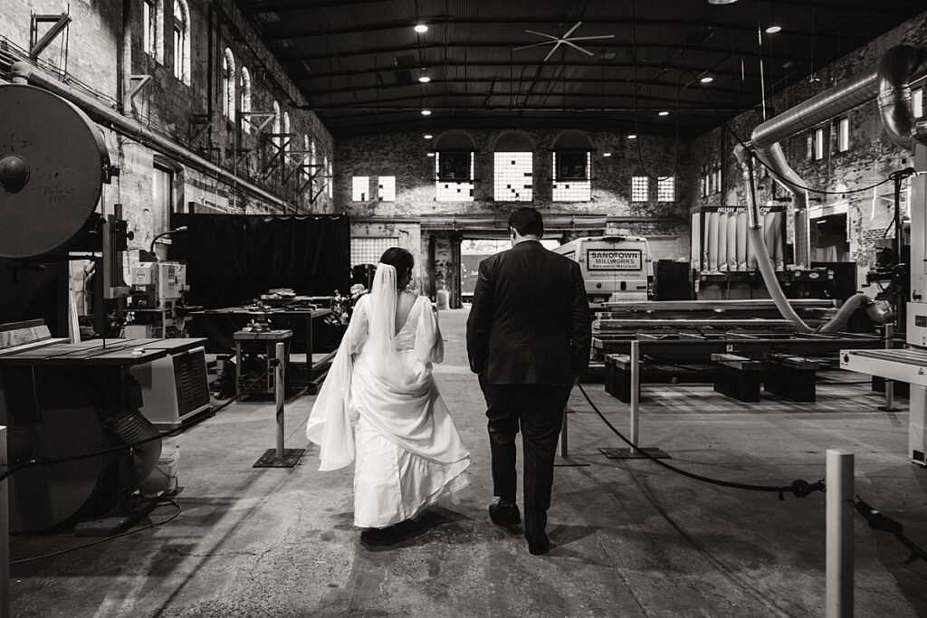 just married couple walking through industrial wedding venue and furniture warehouse at sandtown millworks and the butterfly room