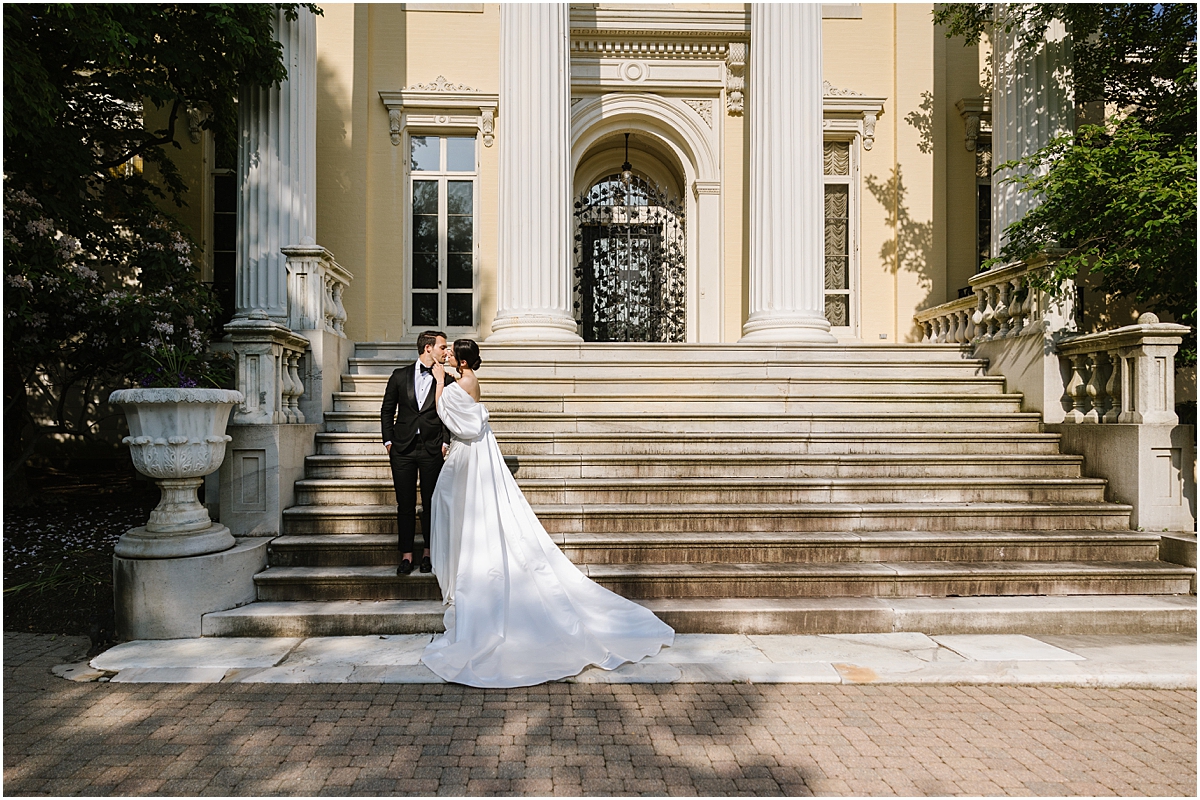 bride and groom standing on front steps about to kiss at Evergreen Museum & Library in North Baltimore