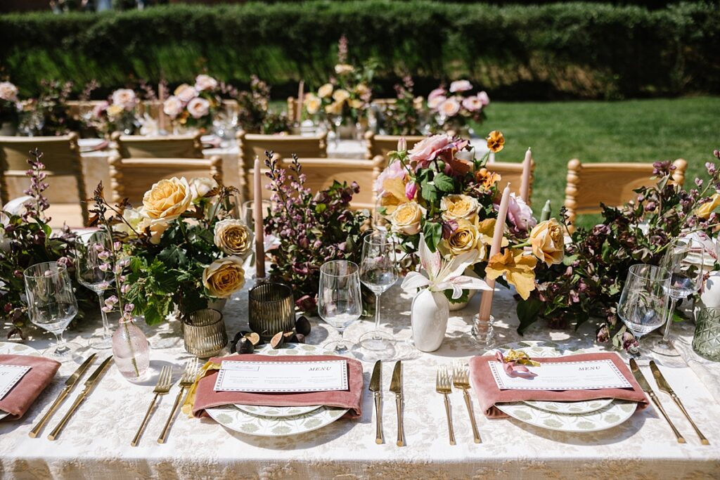 elegant wedding florals and table setup with velvet and patterned linens, menus with fresh figs and smoke gray glassware
