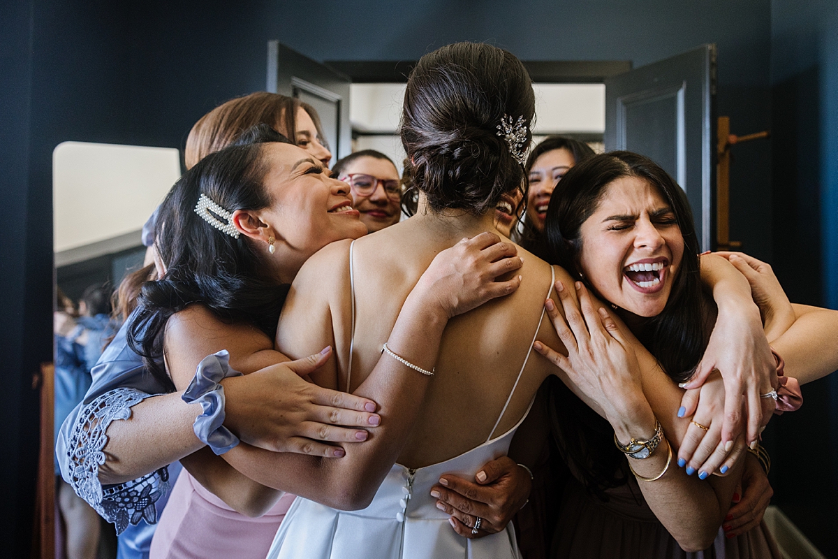 group of girlfriends hugs the bride in the miss mary suite of hotel revival