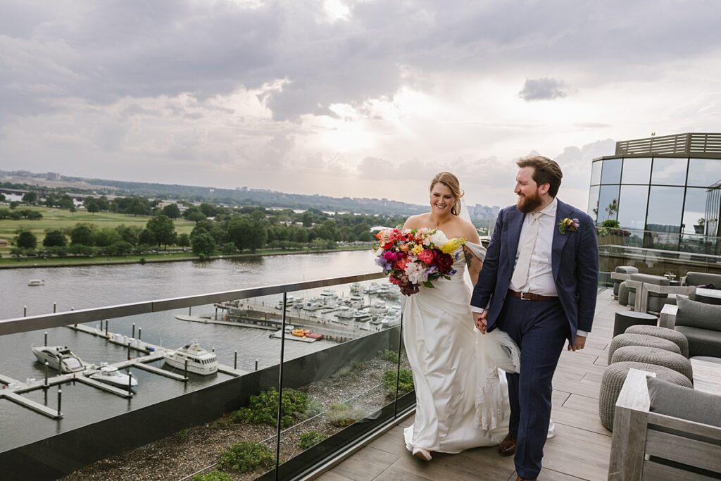 bride and groom walking along rooftop at dc pendry overlooking wharf and potomac river